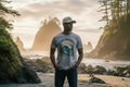 Pacific Northwest Beach Logo Hat on a rocky coastline at golden hour